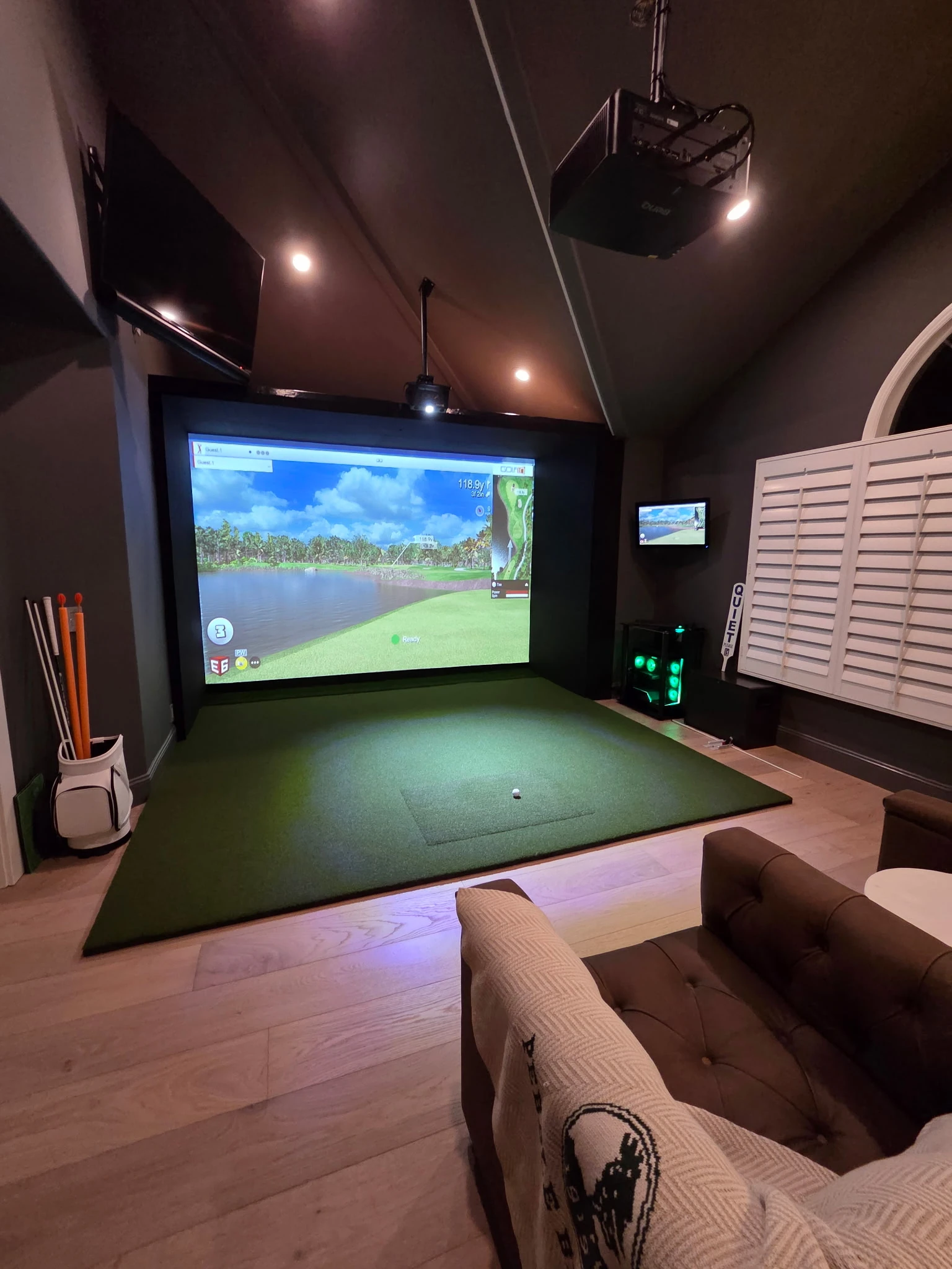 Dedicated home golf room with a custom screen and overhead equipment