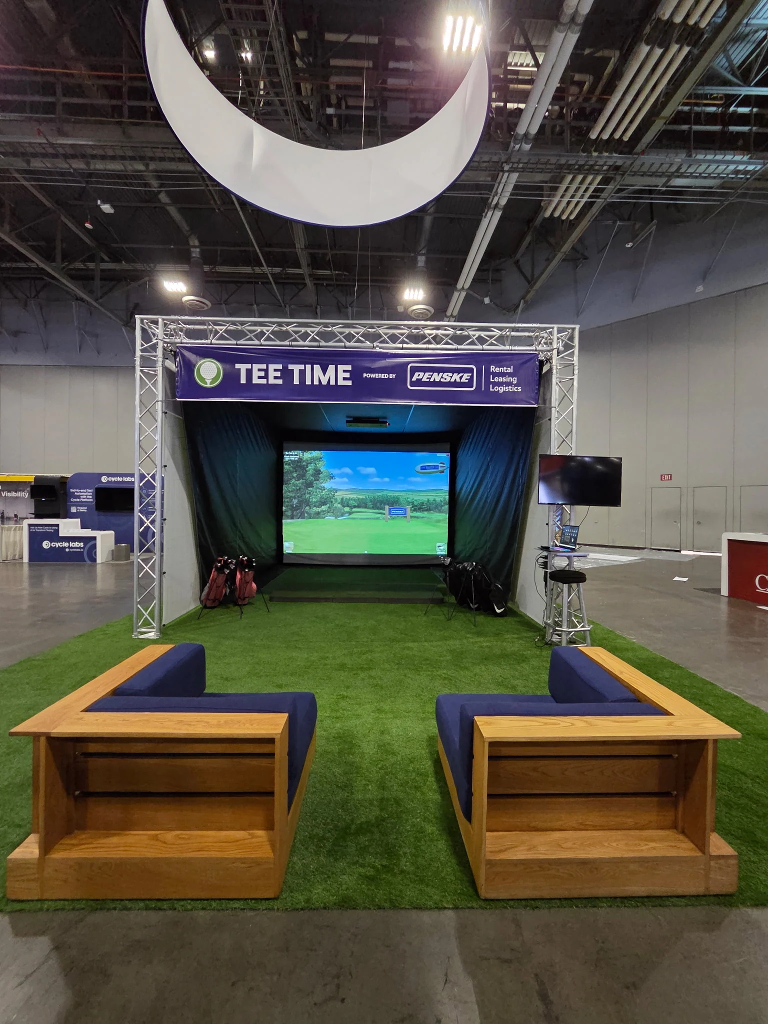 Penske branded golf simulator activation with custom overhead banner and branded on-screen visuals