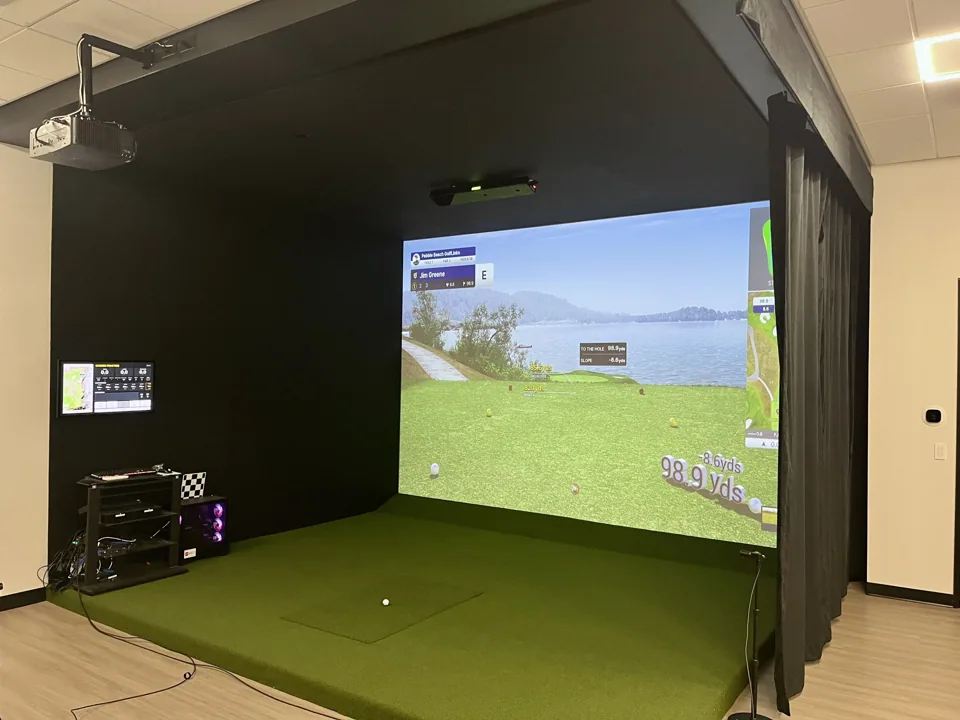 Completed indoor golf simulator installation with integrated screen and hitting area
