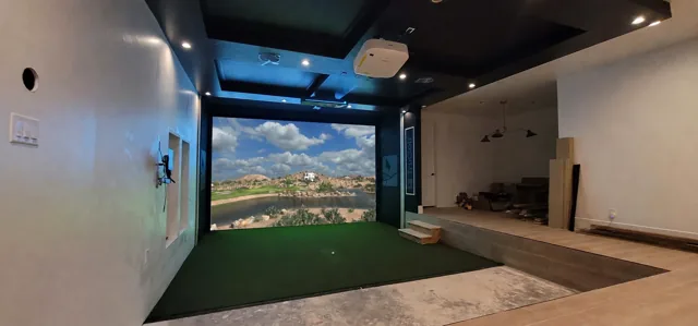 Custom home golf simulator integrated into a room with padded surround, projection and hitting surface