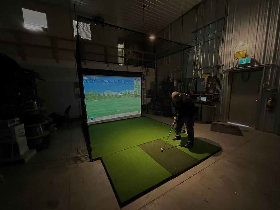 Golf simulator installed within a shared garage and workshop space