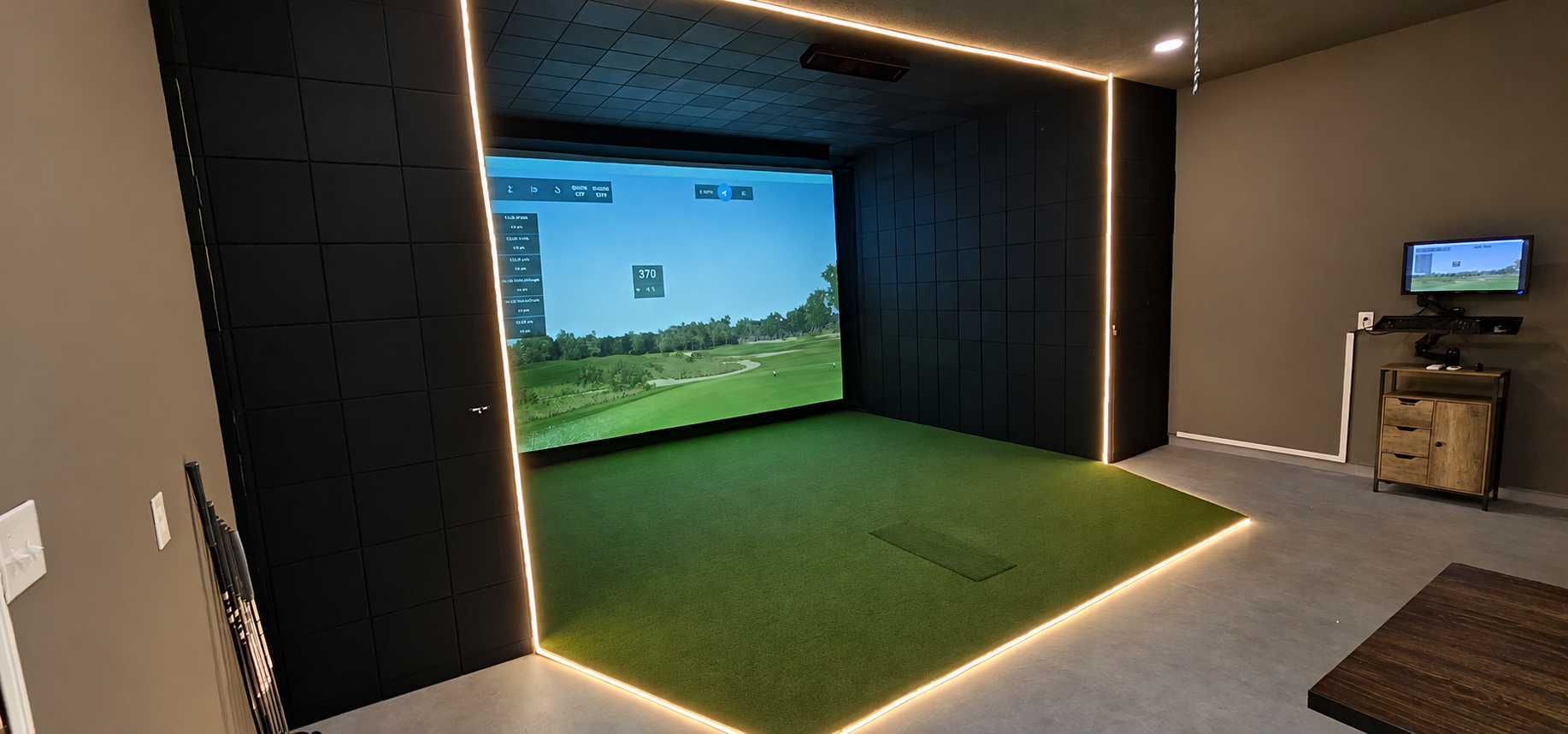 Custom home golf simulator with padded walls, an integrated hitting mat and LED lighting around the enclosure