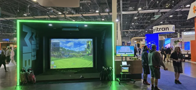 Branded golf simulator rental with illuminated green enclosure at a trade show