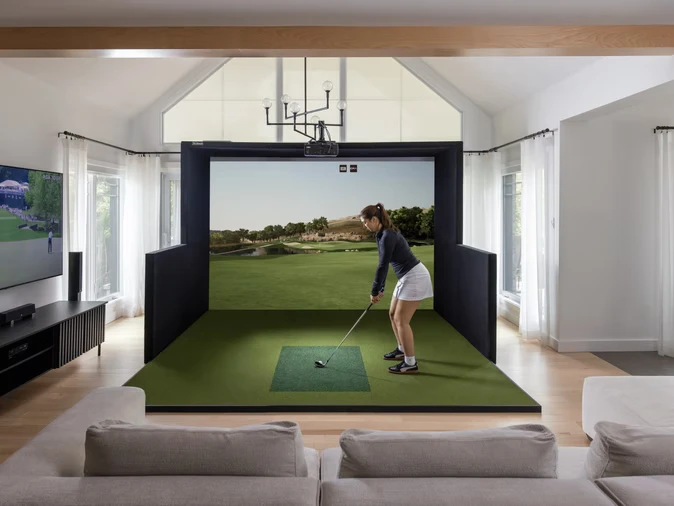 Golfer taking a swing in a SimBooth home simulator